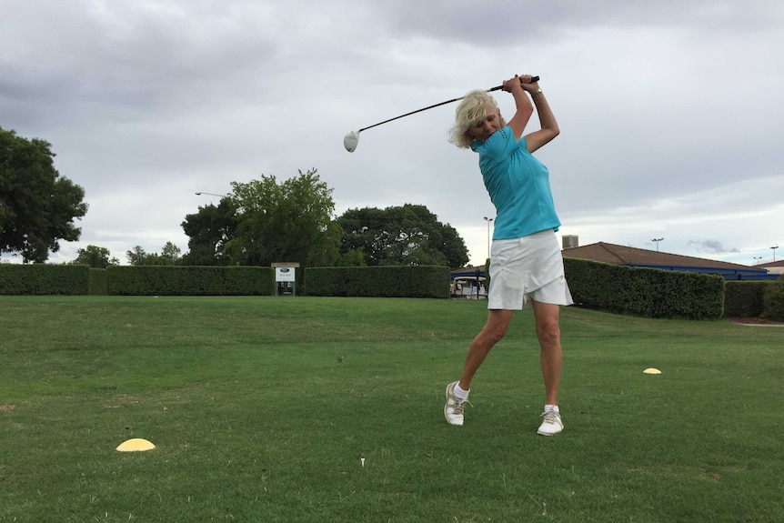 A woman swings a golf club.