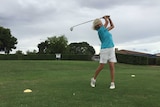 A woman swings a golf club.