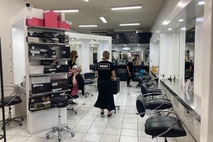 A hairdressing salong with two customers but also empty seats.