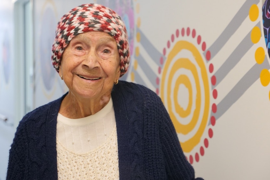 an elderly woman wearing a beanie looking a the camera