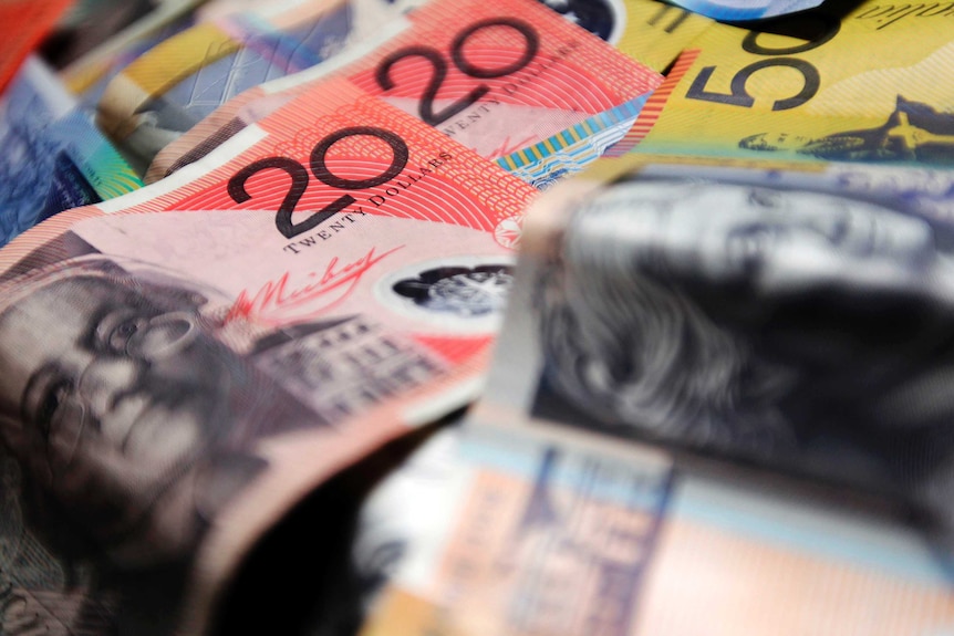 Colourful Australian banknotes in various denominations are arranged for a photograph.