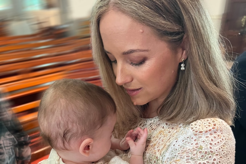 Caitlyn Gribbin looks down at her son, who she is nursing while standing