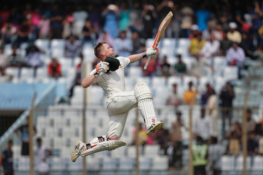 Australia's David Warner jumps in the air in celebration after scoring hundred runs.