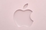 The Apple logo sits on the front of a laptop