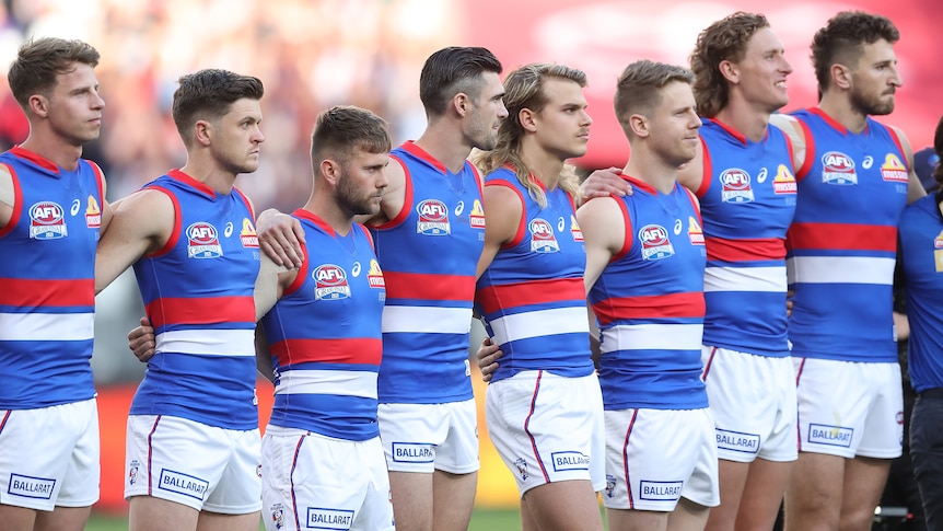AFL player standing arm in arm before a match