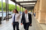 Two men walking side by side along a footpath outside a court building