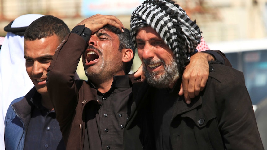 Relatives of those lost in the ferry accident mourn outside the morgue in Mosul, Iraq.