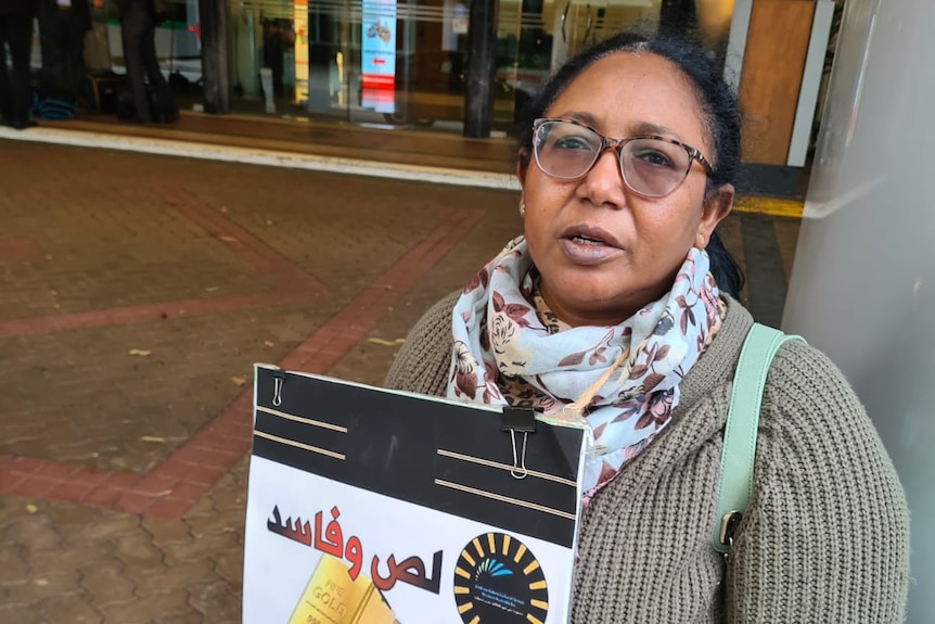 African Australian woman holding protest signs.