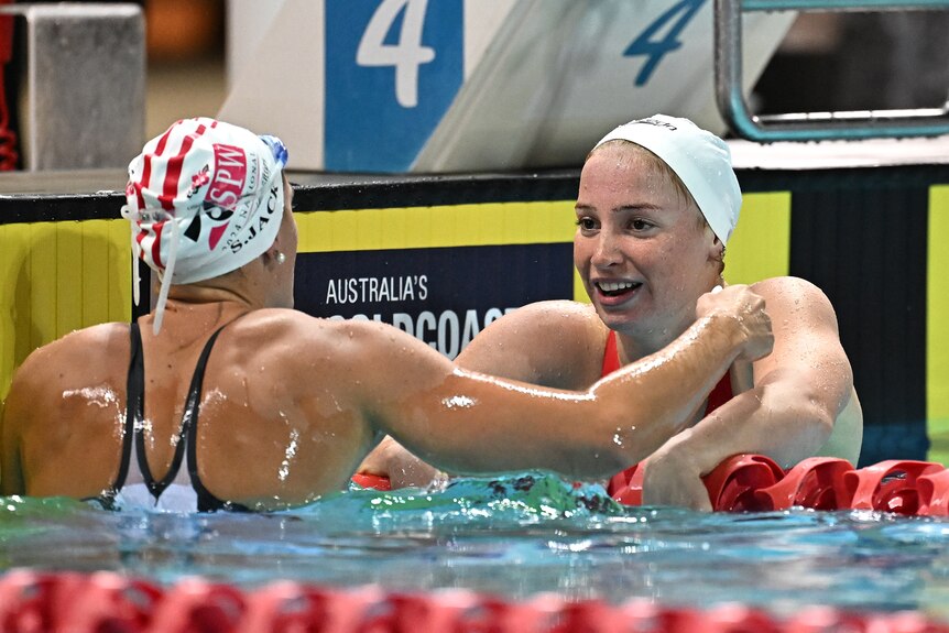 An Australian female swimmer turns to the competitor in the lane next to her after winning a race.