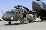 Aerial porters work with maintainers to load a UH-60L Blackhawk helicopter into a U.S. Air Force plane.