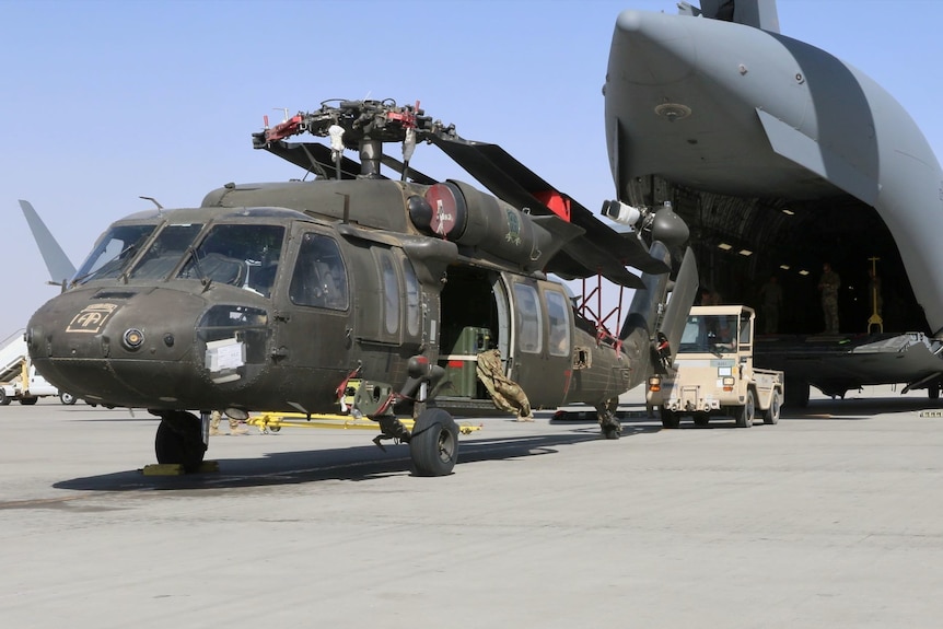 Aerial porters work with maintainers to load a UH-60L Blackhawk helicopter into a U.S. Air Force plane.