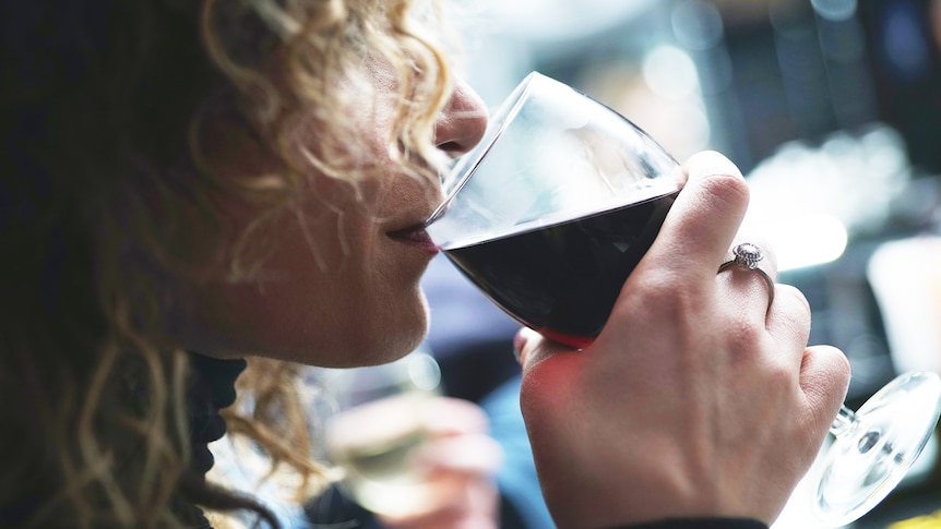 Woman drinking wine from a glass, in a story about drink spiking and the difficulties of reporting it.