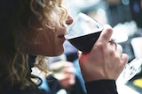 Woman drinking wine from a glass, in a story about drink spiking and the difficulties of reporting it.