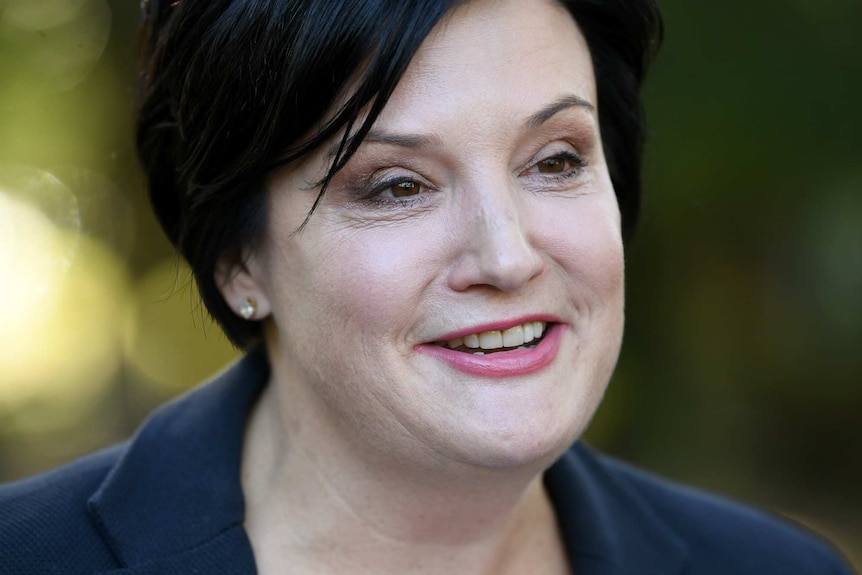 A woman with short dark hair smiling.