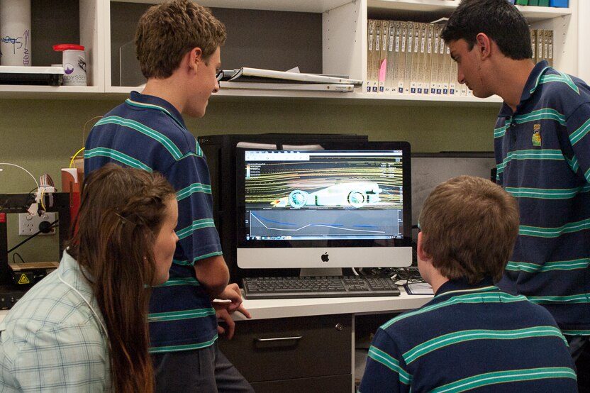 The students look over simulated wind tunnel results of their design.