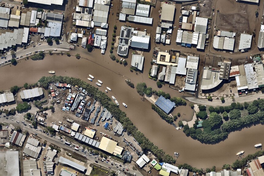 The Brisbane River at Albion, with flooding around buildings on its banks, is seen from above.