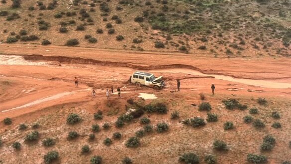 An aerial image of a car and seven people in the bush 