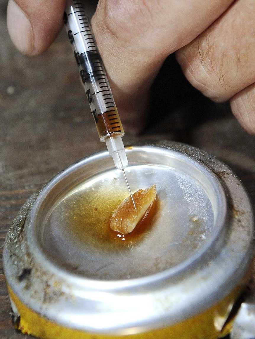 A man prepares to inject heroin