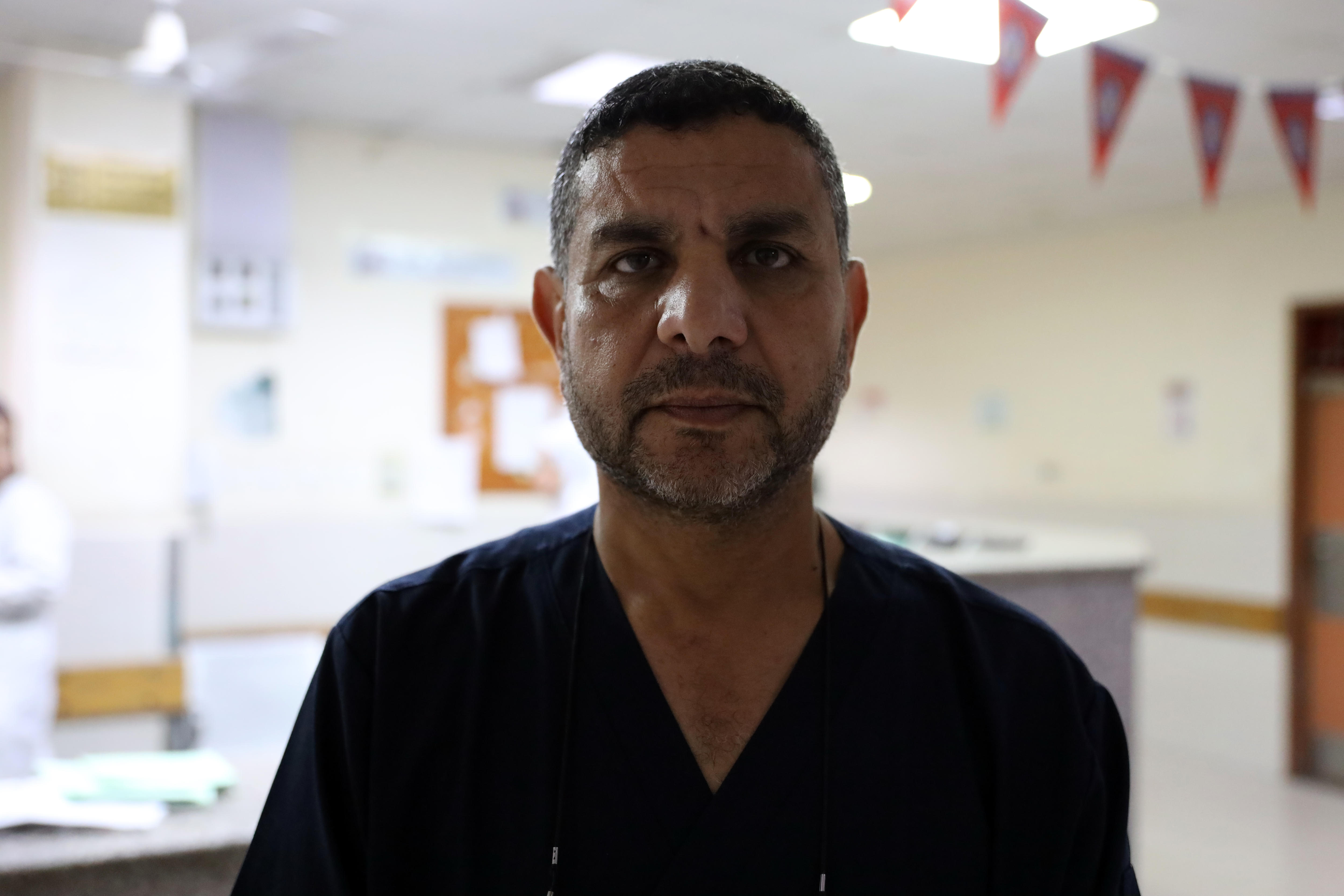 A Palestinian man in a hospital reception looking at the camera.