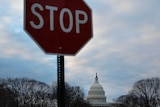A stop sign with the US Capitol building under grey skies
