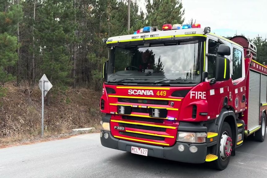 A fire engine drives along a rural road.