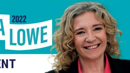 A woman smiling with a pink shirt and black blazer.