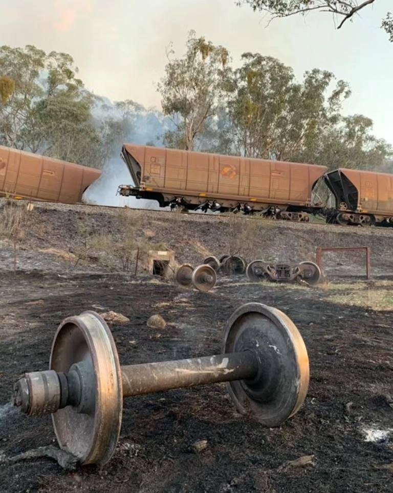 A burnt axel with a derailed train in background