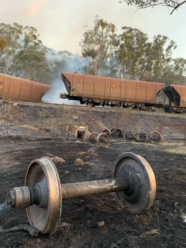 A burnt axel with a derailed train in background