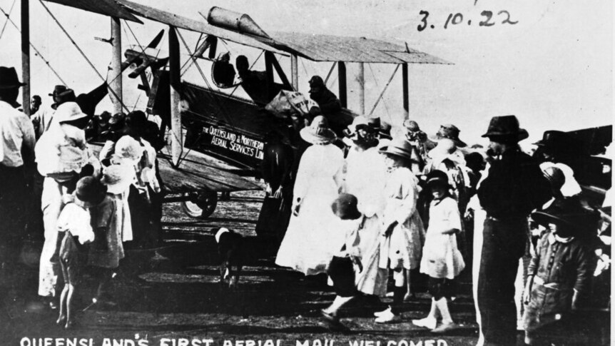 An historic photo of people gathered at an old aeroplane.