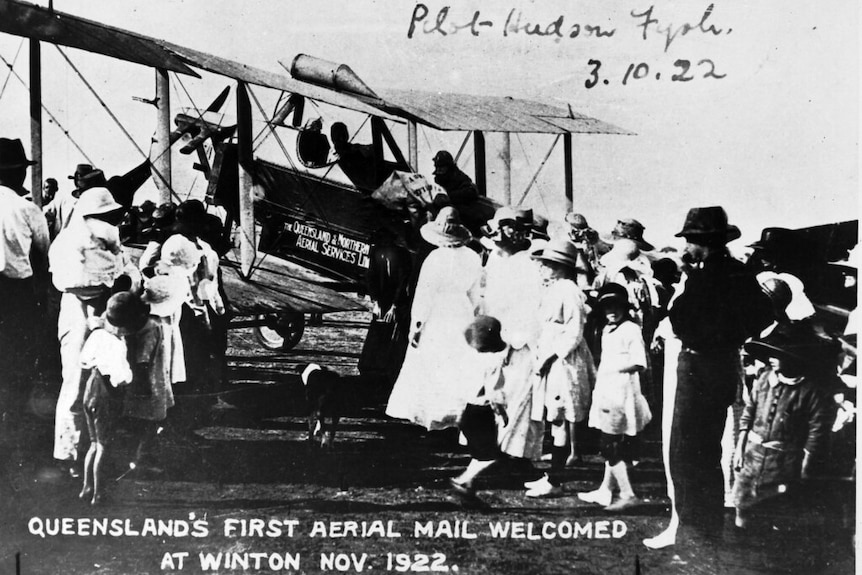 An historic photo of people gathered at an old aeroplane.