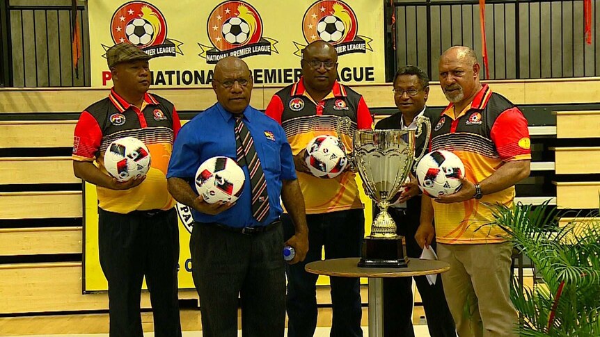 Five officials of the National Premier League stand around a trophy at the league launch.