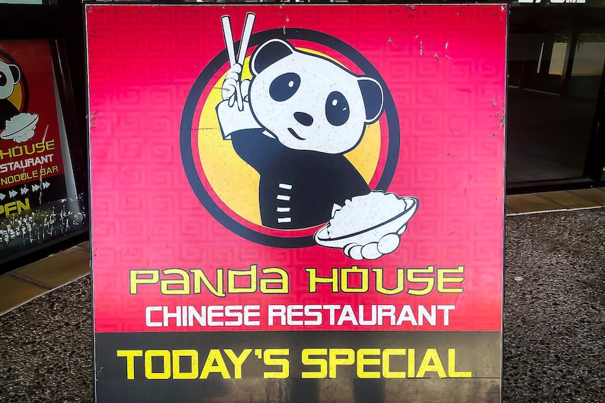 Close up of sandwich board for Panda House, in red and black with a cartoon panda in the centre holding a bowl of rice.