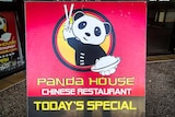 Close up of sandwich board for Panda House, in red and black with a cartoon panda in the centre holding a bowl of rice.