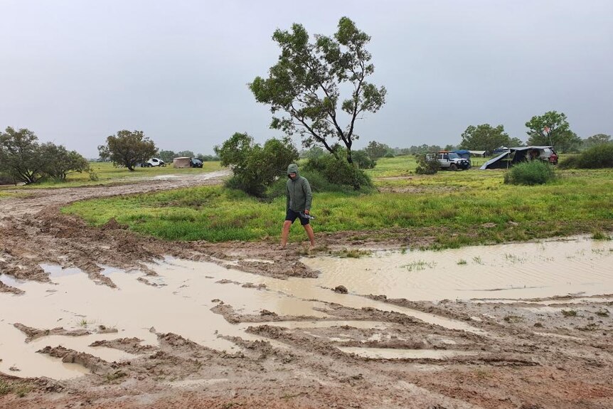 Man walking through mud at camp site in Birdsville