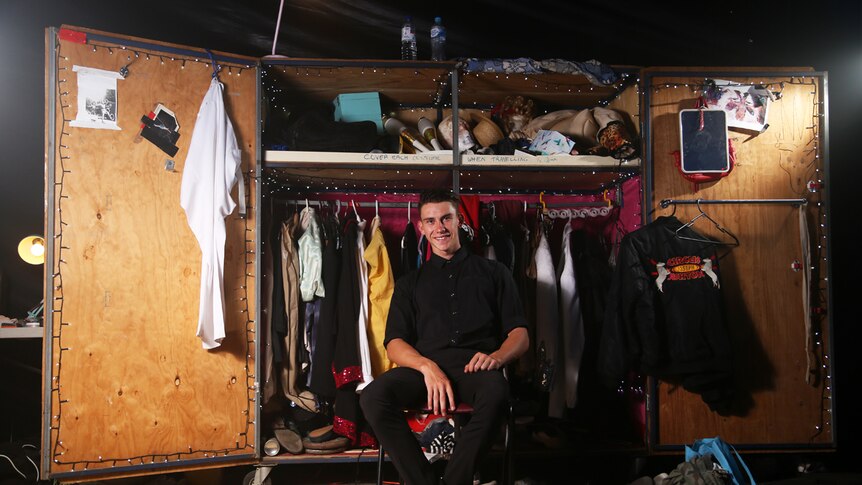 Stagehand Kyle Wishart sits in front of a large wardrobe backstage at Infamous.