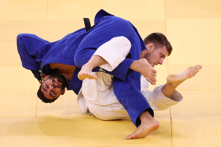 An Israeli judoka in blue grapples with a Canadian competitor in white at the Tokyo Olympics. 