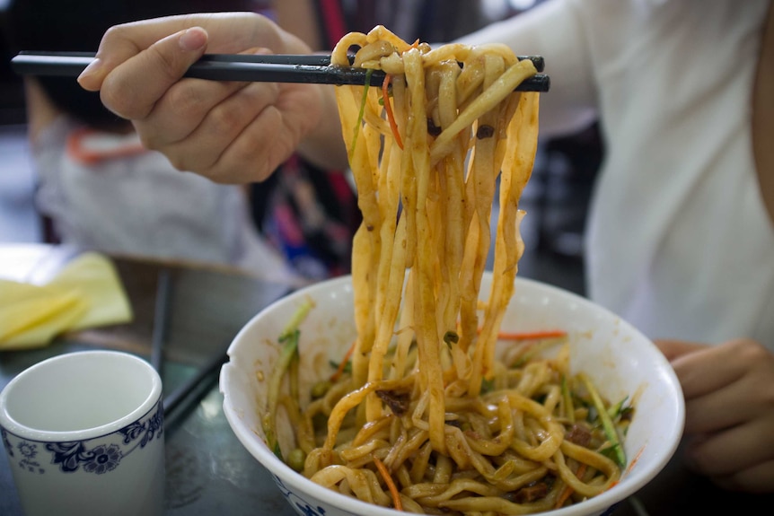 Person eating noodles with chopsticks