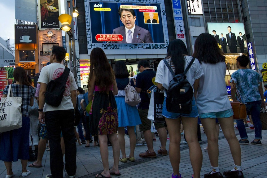 People watch Japan's prime minister Shinzo Abe on a screen