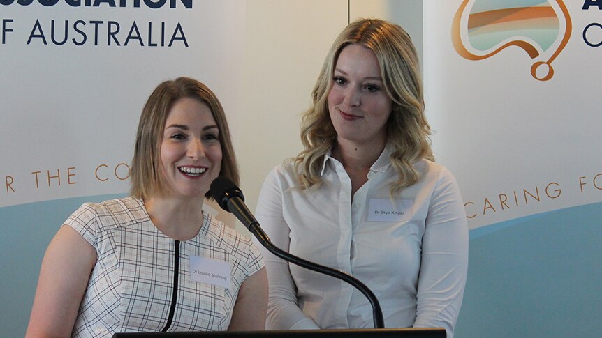 Two women speak from a lectern.