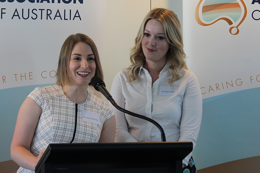 Two women speak from a lectern.