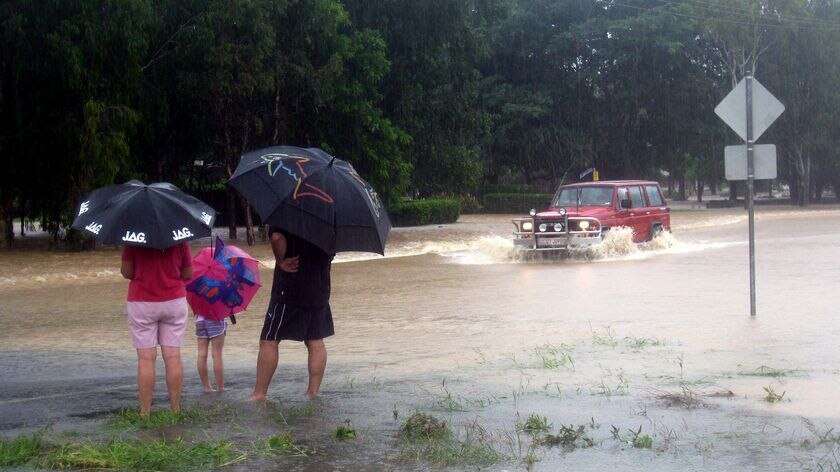A family watches as a four wheel drive crosses Plantation Creek