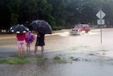 A family watches as a four wheel drive crosses Plantation Creek