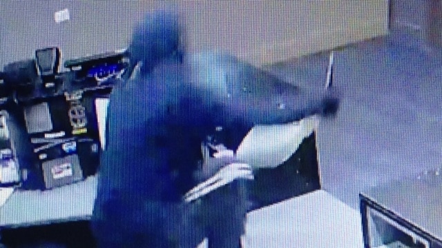 A man holding a knife jumps over the reception desk.