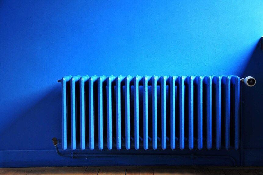 A blue bar heater against a blue wall.