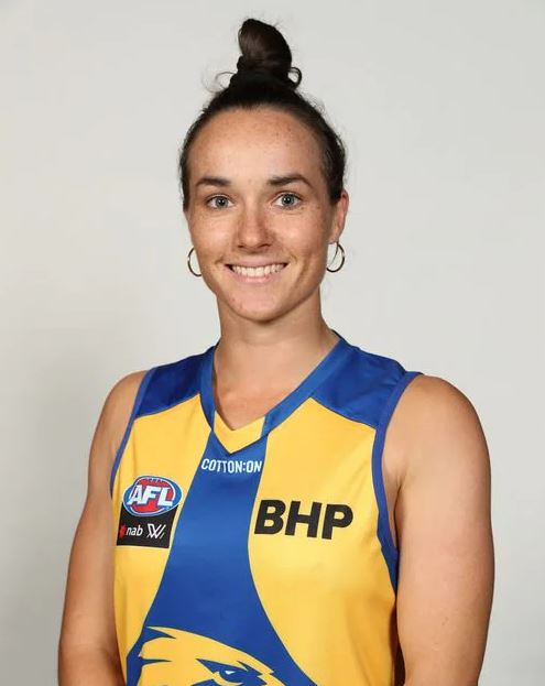 A young woman wearing a football jumper smiling. 