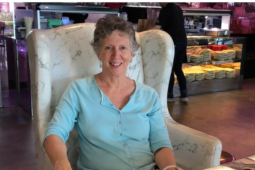 Woman sitting in chair wearing blue cardigan 