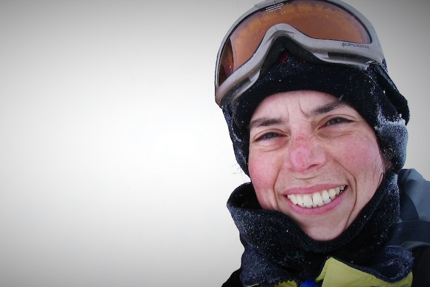 Il fisico del ghiaccio marino della divisione antartica australiana, la dottoressa Petra Hill, in piedi nella neve, sorride alla telecamera.