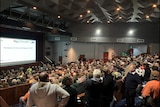 A crowd of people in a auditorium.