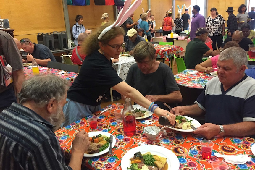 A woman wearing rabbit ears serves food.