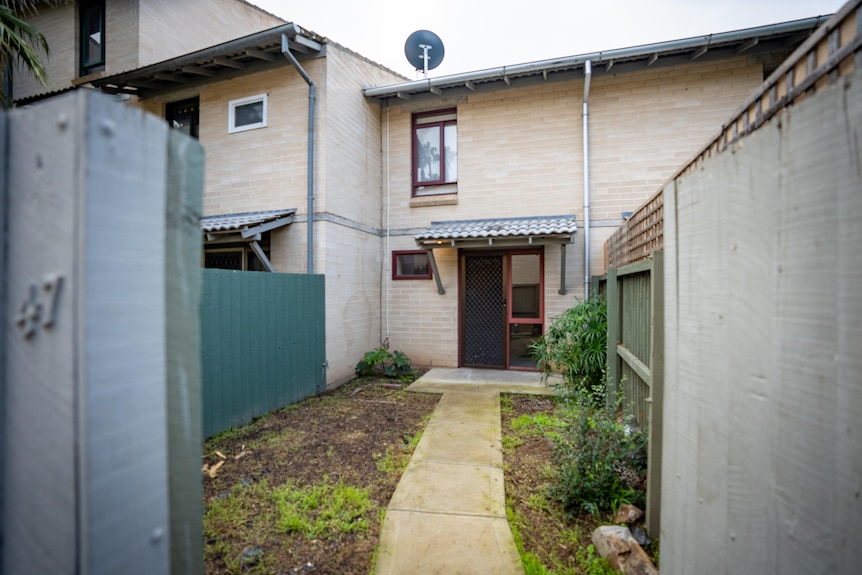 A cement path leads to a modest two-storey brick house